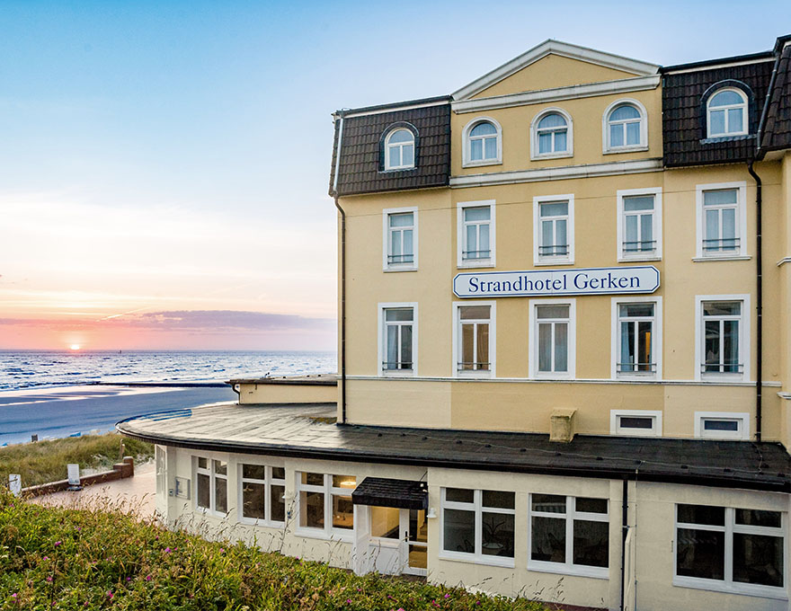 Strandhotel Gerken auf Wangerooge mit Sonnenuntergang im Hintergrund und Blick aufs Meer und Strand
